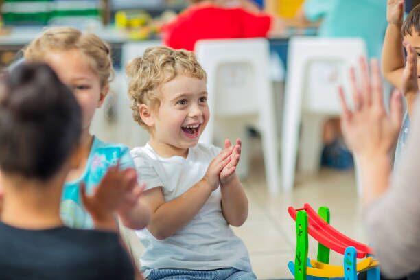 About Us A joyful child clapping during group play at an early learning centre in Perth, showcasing the engaging atmosphere of top childcare centres in Perth.