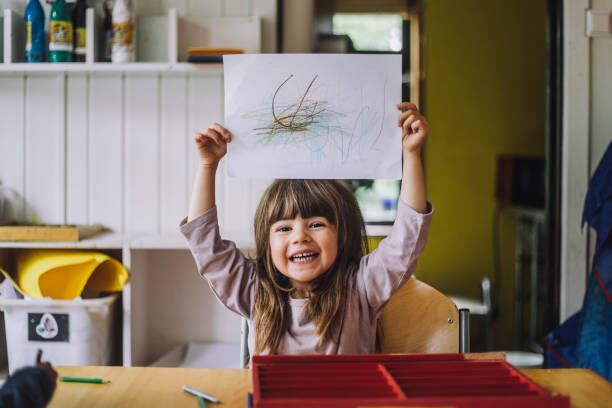 About Us A child proudly displaying their artwork at an early learning centre in Perth.